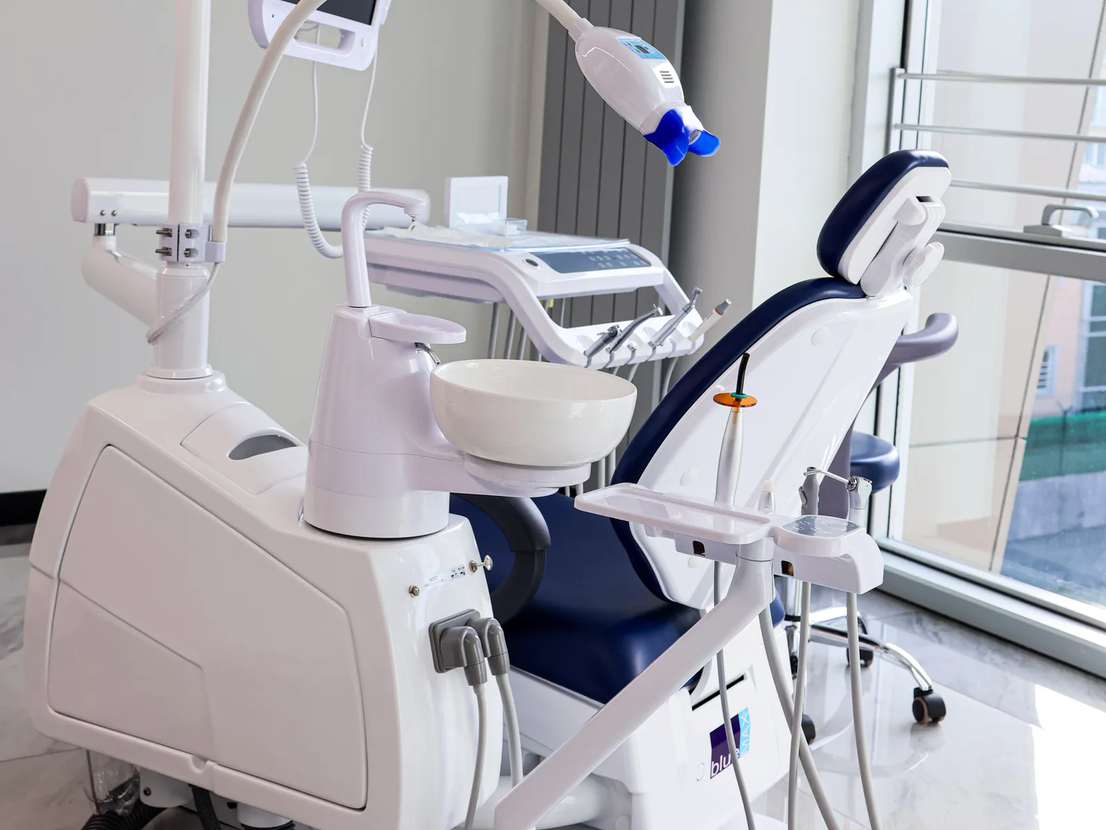 A dental chair with an overhead light in a bright treatment room