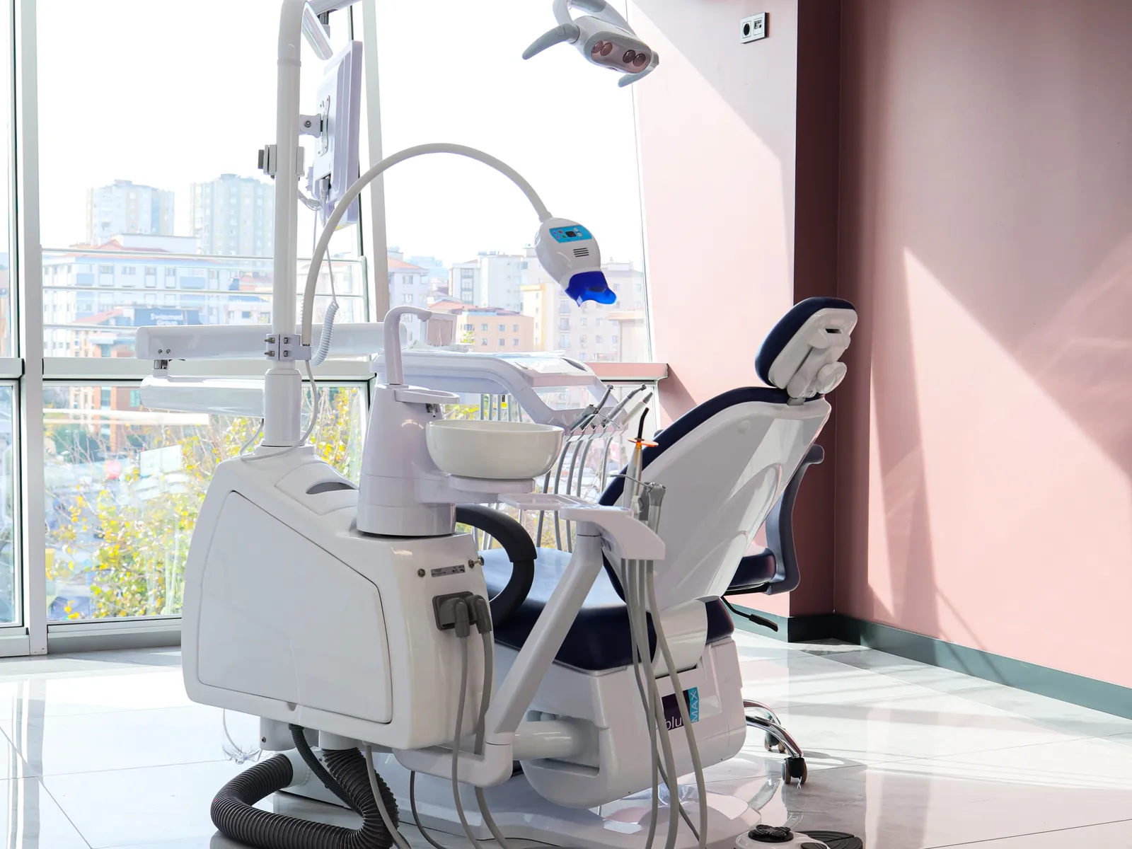 A treatment room with a dental chair beside large windows