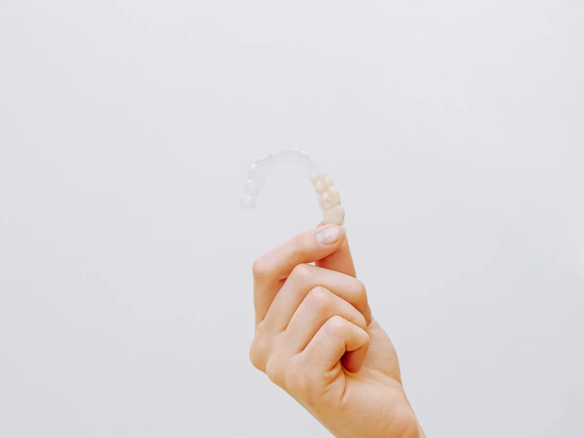 Una mano sujetando un alineador dental transparente